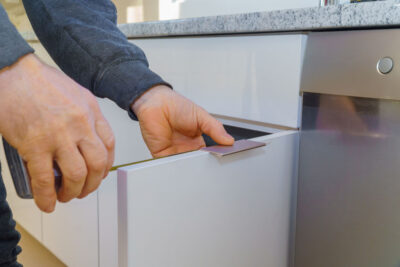 Hand on handle installation of door handles on opening cabinet door in kitchen